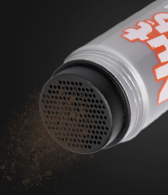Close-up of the Nut Job shaker bottle releasing fine brown hair fibres