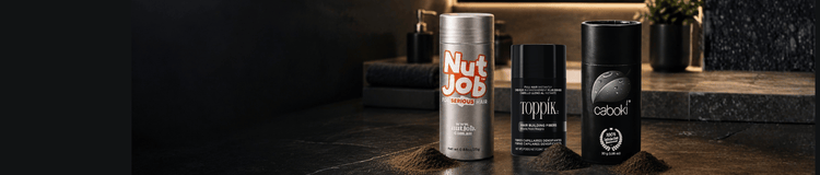 Nut Job, Toppik and Caboki hair building fibre bottles side by side on a dark bathroom bench, fibres piled in front